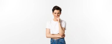 Lgbtq ve gurur konsepti. Tatmin olmuş genç eşcinsel bir adam, bir fikre sahip olmak ve kameraya bakarken gülümsemek, ekşi bluz, beyaz arka plan.