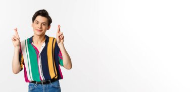 İyimser genç adam gülümsüyor, şans dilemek için şans diliyor, beyaz arka planda duruyor. Boşluğu kopyala