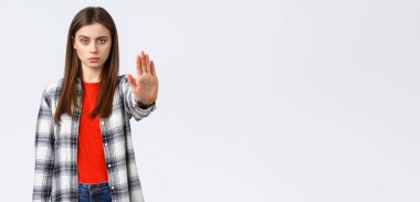 Yaşam tarzı, farklı duygular, boş zaman aktiviteleri konsepti. Durma zamanı. Sıradan giyinmiş ciddi bir genç kadın, yasaklamak, yasaklamak ya da yasaklamak için elini uzat, beyaz arka plan..