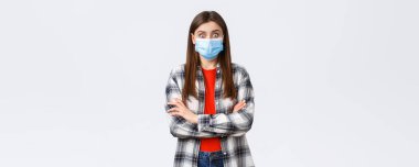 Coronavirus salgını, karantina, sosyal mesafeler ve duygu kavramı. Şaşkınlık içinde, tıbbi maskeli ve günlük kıyafetli mutlu genç bir kadın, şaşkınlık içinde gözler, iyi haberleri dinleyin..