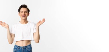 Lgbtq ve gurur konsepti. Mutlu ve tatmin olmuş genç gay adam topaç üstünde alkışlıyor gururla el çırpıyor, kameraya gülümsüyor, beyaz arka planda duruyor..