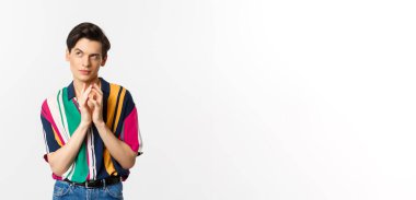 Sinsi genç adamın bir planı var. Çan kulesi gibi parmakları var ve sol üst köşede kurnaz görünüyor. Bir şeyler planlıyor, beyaz arka planda duruyor..