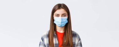 Coronavirus salgını, karantina, sosyal mesafeler ve duygu kavramı. Genç kız öğrencinin yakın çekimi, tıbbi maskeli kız kameraya bakıyor, normal ifade.
