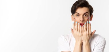 Millet, lgbtq ve güzellik konsepti. Tırnaklarına mavi oje süren, kameraya bakan, manikürlü, beyaz arka planda duran güzel eşcinsel bir adam..