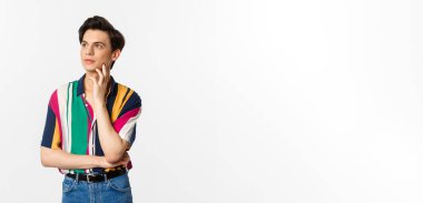 Sol üst köşeye bakan angrodynous genç adam görüntüsü düşünceli, tanıtım okuyor, beyaz arka planda duruyor..