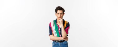 Yakışıklı ve şık bir adamın portresi kameraya düşünceli bakıyor, seçim yapıyor, sana bakmayı düşünüyor, beyaz arka planda duruyor..