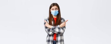 Coronavirus salgını, karantina, sosyal mesafeler ve duygu kavramı. Kararsız genç bir kadın seçim yapıyor. Tıbbi maskeli bir kız karar verirken şaşırmış, yan gözle bakıp, düşünüyor..
