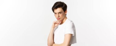 Millet, lgbtq ve güzellik konsepti. Güzel çift cinsiyetli erkek model. Yüzünde sim var. Kırpık bluz giyiyor, kameraya delici gözlerle bakıyor..