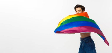 İnsan hakları ve lgbtq toplum kavramı. Yüzünde parıltı olan genç bir ibne gururla lgbtq bayrağı sallıyor, beyaz arka planda duruyor..