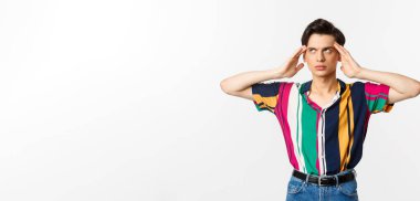 Sinirli eşcinsel adam gözlerini deviriyor ve üzgün bakıyor, bir şeyden rahatsız olmuş, beyaz arka planda duruyor..