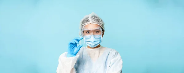 주사로 주사기를 보안경을 이시아인 의사의 사진을 클로즈업하고 독감이나 파란색 배경으로 — 스톡 사진