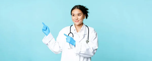 Sonriente Médico Asiático Trabajador Médico Uniforme Señalando Mirando Izquierda Espacio — Foto de Stock