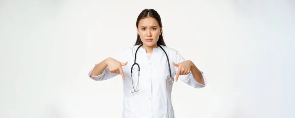 Zklamaný Asijský Lékař Ukazuje Prsty Dolů Zamračený Vypadá Znepokojeně Ukazuje — Stock fotografie