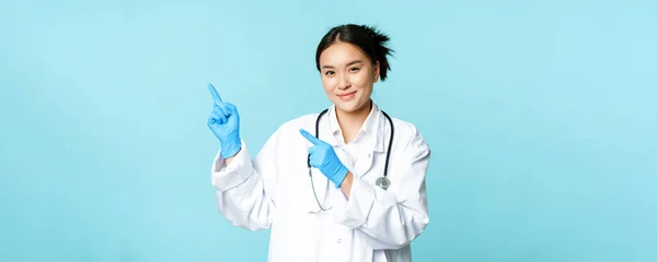 Lächelnde Ärztin Ärztin Arztuniform Und Sterilen Handschuhen Zeigefinger Links Auf — Stockfoto