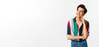 Düşünceli gülümseyen eşcinsel adam sol üst köşeye bakıyor, bir şeyler canlandırıyor, beyaz arka planda duruyor..