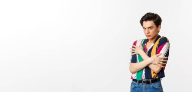 Ürkek eşcinsel adam görüntüsü kameraya karşı hoşnutsuz görünüyor, kendini savunuyor, beyaz arka planda duruyor..