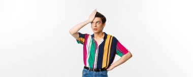 Sinirli eşcinsel adam facepalm ve yuvarlanan gözler, beyaz arka plan üzerinde hayal kırıklığına uğramış ve yorgun duruyor..