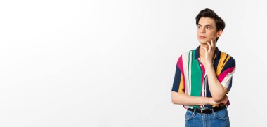 Sol üst köşeye bakan angrodynous genç adam görüntüsü düşünceli, tanıtım okuyor, beyaz arka planda duruyor..