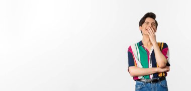 Yakışıklı bir delikanlının şakaya gülüşü, eğlenişi, ağzı ellerle kapatması ve kıkırdaması, beyaz arka planda durması..