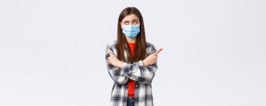 Coronavirus salgını, karantina, sosyal mesafeler ve duygu kavramı. Kararsız genç bir kadın seçim yapıyor. Tıbbi maskeli bir kız karar verirken şaşırmış, yan gözle bakıp, düşünüyor..
