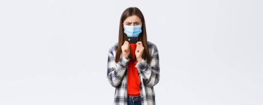 Coronavirus salgını, evden çalışma, online alışveriş ve temassız ödeme konsepti. Kızgın ya da hayal kırıklığına uğramış, tıbbi maskeli, hoşnutsuz, elinde kredi kartı olan genç bir kadın..