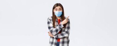 Coronavirus salgını, karantina, sosyal mesafeler ve duygu kavramı. Heyecanlı ve sevinçli, tıbbi maskeli genç kız, parmak ucunda sağ üst köşedeki inanılmaz reklamı gösteriyor..