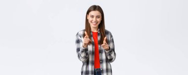 Yaşam tarzı, farklı duygular, boş zaman aktiviteleri konsepti. Hevesli ve mutlu, sıradan kıyafetli genç bir kız kamerayı işaret ediyor, anladım ya da tebrik ediyorum, seni seçiyor..