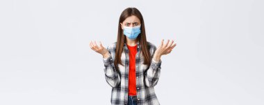 Coronavirus salgını, karantina, sosyal mesafeler ve duygu kavramı. - Neler oluyor? Kafası karışmış ve sıkıntılı genç bir kadın cevap istiyor, omuz silkiyor, üzgün üzgün..