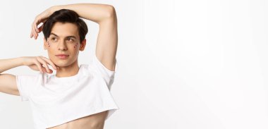 Kameraya poz veren, beyaz arka planda duran çift cinsiyetli güzel adamın yakın çekimi..