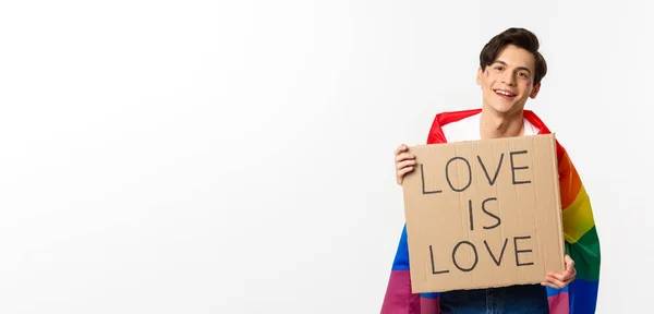 笑顔ゲイの男活動家保持サイン愛は愛のための愛ですLbtプライドパレード レインボーフラグを身に着けています 白い背景の上に立って — ストック写真
