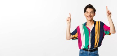 Yakışıklı, şık giyinmiş, logo gösteren, parmaklarını havaya kaldıran ve gülümseyen, beyaz arka planda duran tuhaf adam..