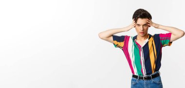 Arsız çift cinsiyetli adam kameraya bakıyor, delici bakışlarla sana bakıyor, beyaz arka planda duruyor..