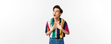 Etkileyici genç yakışıklı adam sol üst köşeye bakıyor, inanmadığını ve şaşırdığını ifade ediyor, reklam teklifini görüyor, beyaz arka plan.