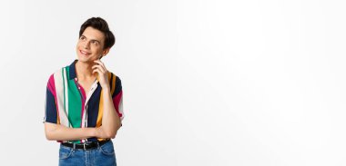 Düşünceli gülümseyen eşcinsel adam sol üst köşeye bakıyor, bir şeyler canlandırıyor, beyaz arka planda duruyor..