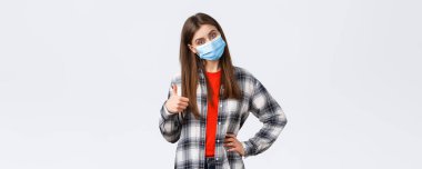 Coronavirus salgını, karantina, sosyal mesafeler ve duygu kavramı. Tıbbi maske takan kendine güvenen güzel bir kadın tavsiye verir, tavsiye eder, tanıtım önerir, onayını alır..