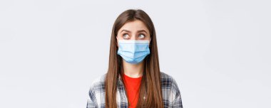Coronavirus salgını, karantina, sosyal mesafeler ve duygu kavramı. Medikal maskeli, düşünceli genç bir kadının yakın çekimi, sol üst köşedeki okuma işaretine bakın ya da kabarcık düşüncesi.