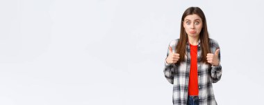 Yaşam tarzı, farklı duygular, boş zaman aktiviteleri konsepti. Fena değil sanırım. Güzel kız olumlu sonuç alınca şaşırdı, baş parmağını kaldırdı ve şaşkın bir ifade takındı, beyaz arka plandaydı..