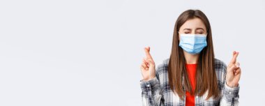 Coronavirus salgını, karantina, sosyal mesafeler ve duygu kavramı. Dilek tutan, gözlerini kapayan ve şans dileyen umut dolu, hayalperest genç kızın yakın çekimi..