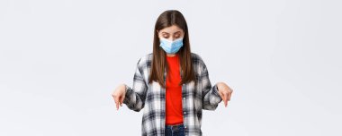 Coronavirus salgını, karantina, sosyal mesafeler ve duygu kavramı. Tıp maskeli çekici tatlı kız. Virüs enfeksiyonundan plazma giymiş bir kadın aşağıya bakıyor..