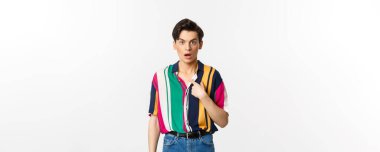 Kendini işaret eden, kafası karışmış, beyaz arka planda duran şaşırmış bir adam..