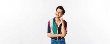 Düşünceli gülümseyen eşcinsel adam sol üst köşeye bakıyor, bir şeyler canlandırıyor, beyaz arka planda duruyor..