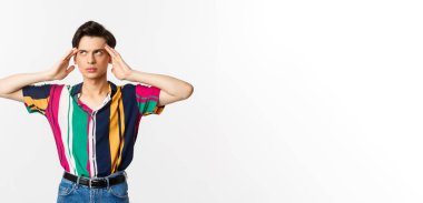 Sinirli eşcinsel adam gözlerini deviriyor ve üzgün bakıyor, bir şeyden rahatsız olmuş, beyaz arka planda duruyor..