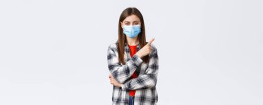 Coronavirus salgını, karantina, sosyal mesafeler ve duygu kavramı. Tıbbi maskeli mutlu genç kadın sağ üst parmağıyla işaret eden Coperid-19 hakkında bilgi verir..