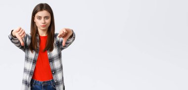 Yaşam tarzı, farklı duygular, boş zaman aktiviteleri konsepti. Şüpheci ve hayal kırıklığına uğramış genç bir kadın tatminsiz bir sırıtış ve hoşnutsuzlukla, onaylamamakla ve kötü ürünleri yargılamakla reddediyor..