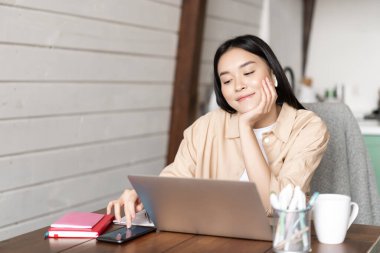 Gülümseyen Asyalı kız öğrenci, dizüstü bilgisayarla evde oturan kadın, akıllı telefon sosyal medyası kaşları çatan ve online ders arasında dinlenen, Webinar 'ı bekleyen..