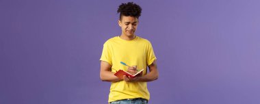 Ödevlerle ilgili sorunları olan, sırıtan, suratını buruşturan, matematik denklemini çözmeye çalışan, deftere not alan, doldurma çizelgesini dolduran keyifsiz ve rahatsız genç bir adamın portresi..