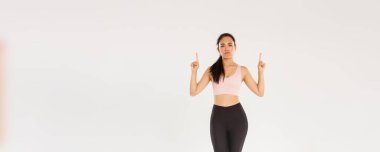 Spor, spor salonu ve sağlıklı vücut konsepti. Eğlendirilmemiş ve şüpheci fitness kızı, spor giyim sektöründe Asyalı bayan sporcu şikayetçi, küskün, hoşnutsuz ve parmakla işaret eden beyaz arka plan.