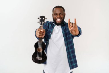 Genç ve yakışıklı Afro-Amerikan adam beyaz arka planda ukulele çalıyor.