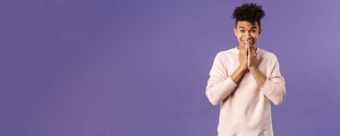 Aptal ve heyecanlı, mutlu gülümseyen hippi adam, mutluluğu içinde tutamıyor, sonunda teslimat kutusunu açmak için cezbedici, dudağının yanında el ele tutuşup, beklentiyle, mor arka planda..