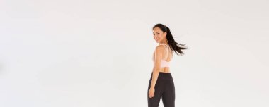 Aktif ve sağlıklı Asyalı fitness kızı, sporcu kadın kameraya tatmin olmuş bir şekilde bakıyor, beden eğitimi koçu antrenmanlara başlıyor, beyaz arka plan..